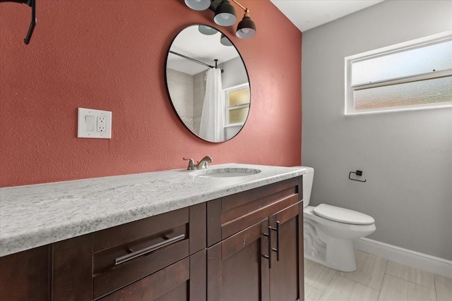 bathroom featuring toilet, vanity, and baseboards