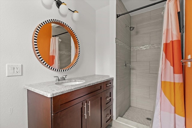 full bathroom with a tile shower and vanity