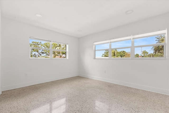 empty room with speckle patterned floor, baseboards, and recessed lighting