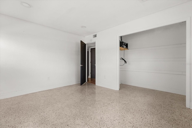 unfurnished room featuring speckled floor and baseboards