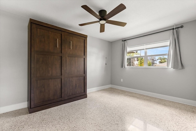 unfurnished bedroom with speckle patterned floor, baseboards, and ceiling fan