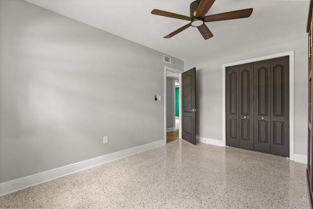 unfurnished bedroom featuring speckled floor, a closet, baseboards, and a ceiling fan