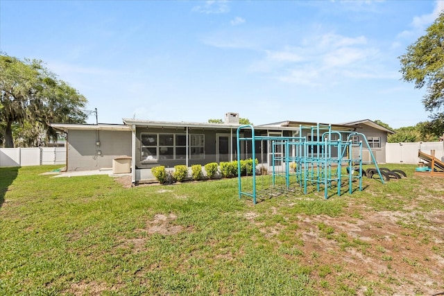 back of house featuring a playground and a sunroom