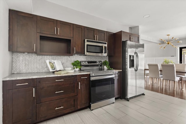kitchen featuring stainless steel appliances, decorative backsplash, dark brown cabinets, a chandelier, and light countertops