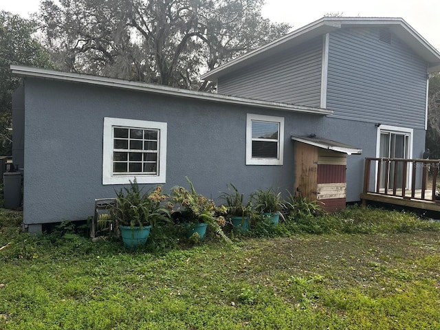 back of property with a wooden deck and a lawn