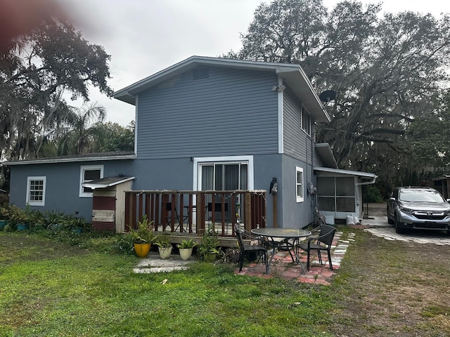 rear view of property featuring a sunroom and a lawn