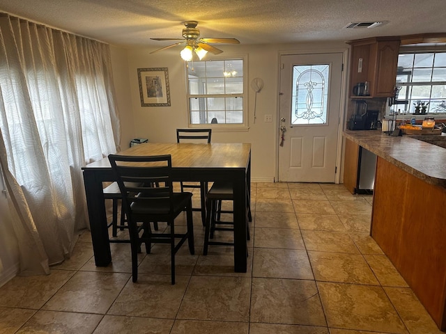 dining space featuring a textured ceiling, ceiling fan, and light tile patterned floors