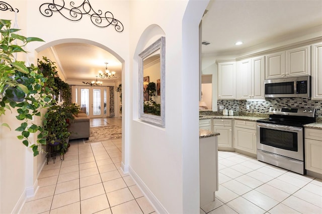 kitchen featuring an inviting chandelier, light tile patterned floors, appliances with stainless steel finishes, and light stone counters