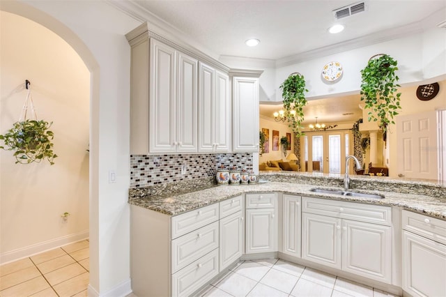 kitchen featuring decorative backsplash, sink, white cabinetry, ornamental molding, and light tile patterned floors