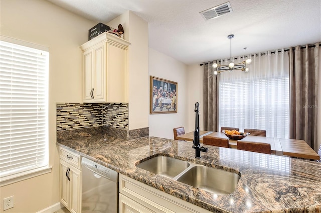 kitchen featuring tasteful backsplash, decorative light fixtures, dishwasher, cream cabinets, and sink