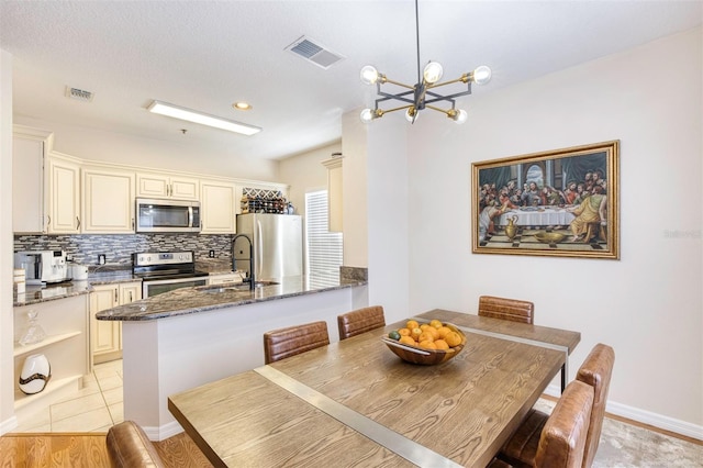 dining space featuring sink, a notable chandelier, and light wood-type flooring