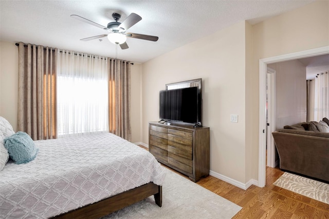 bedroom with ceiling fan, wood-type flooring, and a textured ceiling