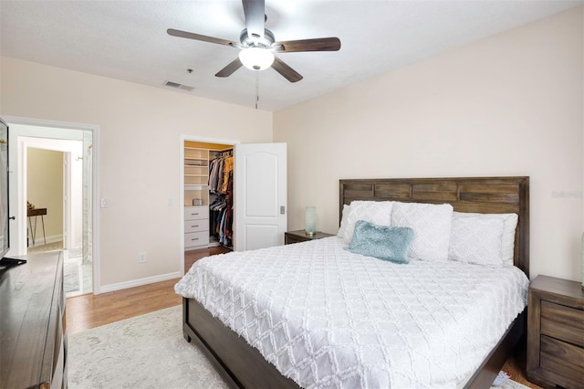 bedroom featuring a spacious closet, ceiling fan, a closet, and light wood-type flooring