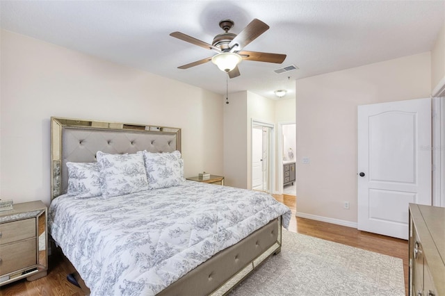 bedroom with ceiling fan, ensuite bathroom, and light wood-type flooring