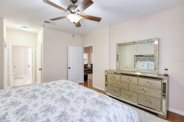 bedroom with ceiling fan, wood-type flooring, ensuite bathroom, and a textured ceiling