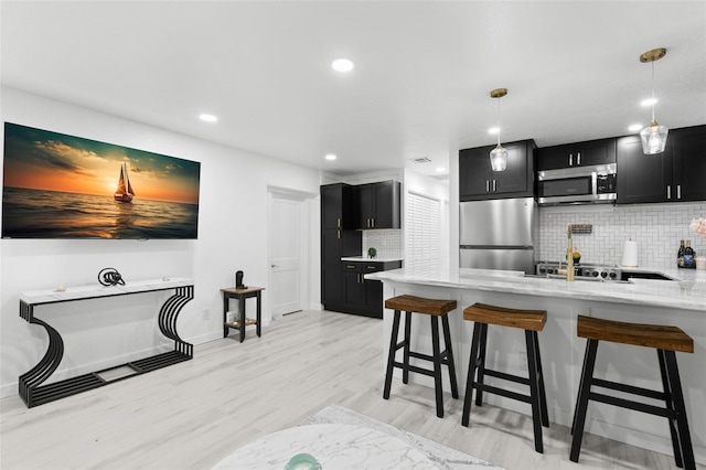 kitchen with kitchen peninsula, pendant lighting, backsplash, a breakfast bar area, and stainless steel appliances