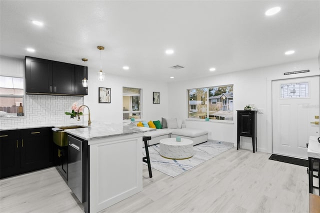 kitchen featuring kitchen peninsula, pendant lighting, a breakfast bar area, and light stone countertops