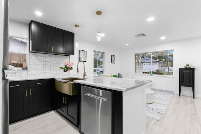 kitchen featuring light stone countertops, pendant lighting, decorative backsplash, sink, and kitchen peninsula