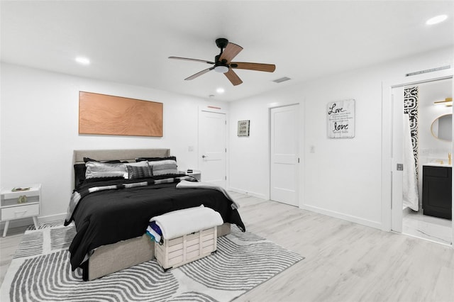 bedroom with ceiling fan, ensuite bath, and light wood-type flooring