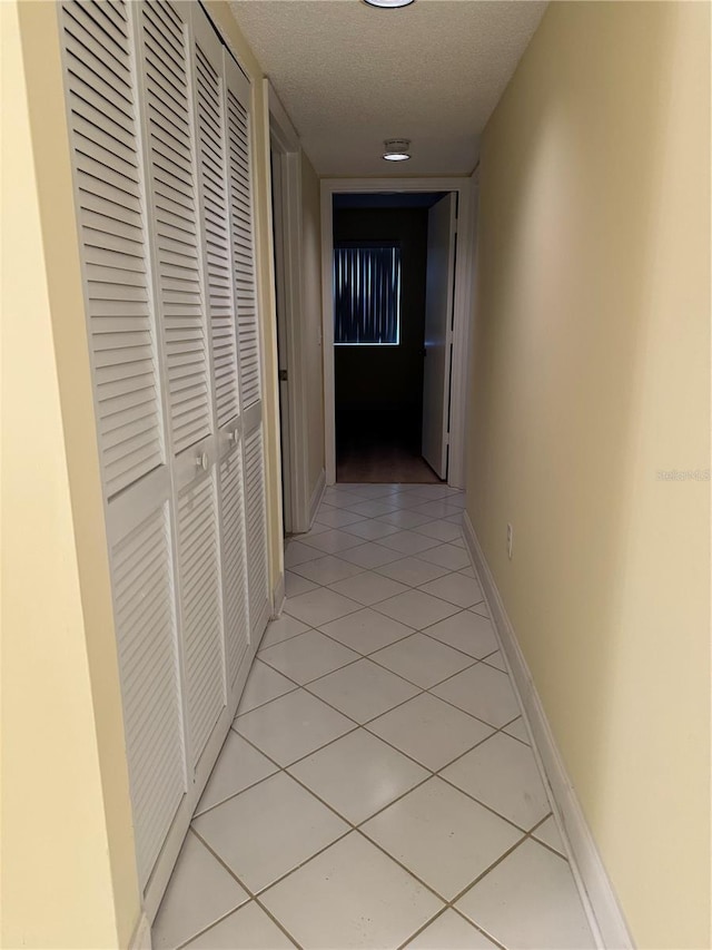 corridor featuring a textured ceiling and light tile patterned floors