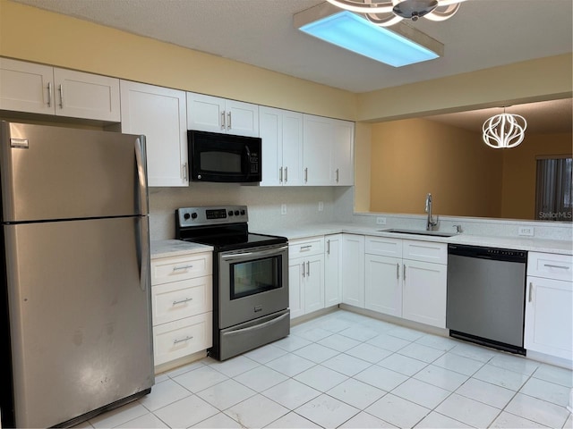 kitchen with white cabinetry, stainless steel appliances, sink, hanging light fixtures, and a notable chandelier