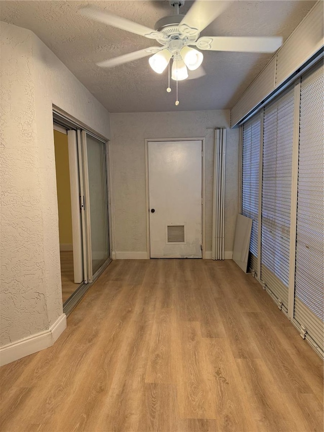 unfurnished bedroom with ceiling fan, a closet, a textured ceiling, and light hardwood / wood-style floors