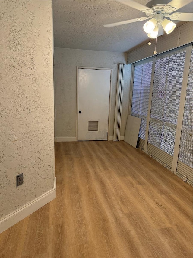 interior space with ceiling fan, a textured ceiling, and hardwood / wood-style flooring