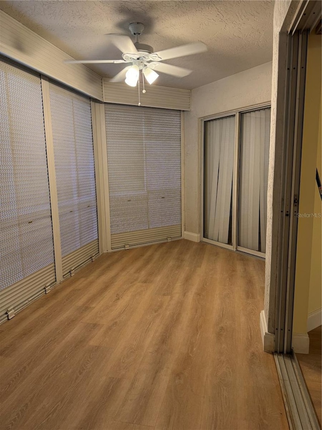 unfurnished bedroom with ceiling fan, a closet, a textured ceiling, and hardwood / wood-style flooring