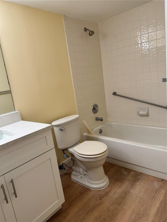 full bathroom featuring toilet, tiled shower / bath combo, hardwood / wood-style flooring, and vanity