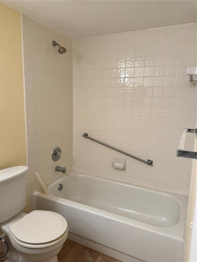 bathroom with toilet, tiled shower / bath combo, and hardwood / wood-style floors