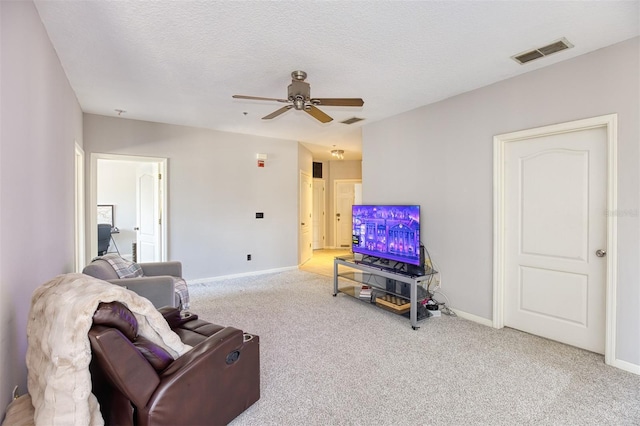 living room with a textured ceiling, ceiling fan, and light colored carpet