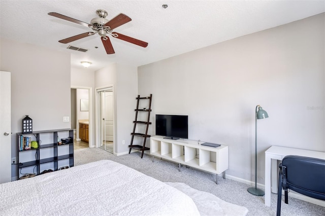 bedroom featuring a textured ceiling, ceiling fan, light colored carpet, and ensuite bath