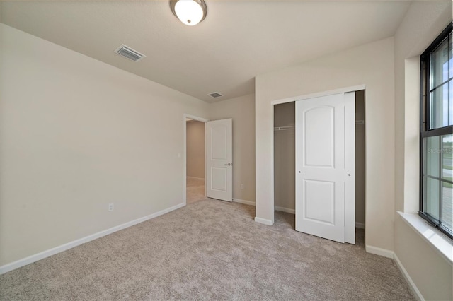 unfurnished bedroom with multiple windows, a closet, and light carpet