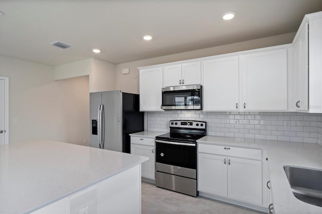 kitchen with white cabinets, backsplash, and stainless steel appliances