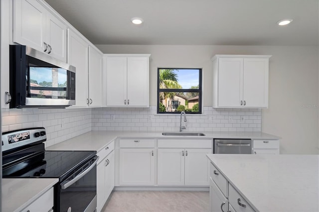 kitchen featuring tasteful backsplash, sink, stainless steel appliances, and white cabinetry