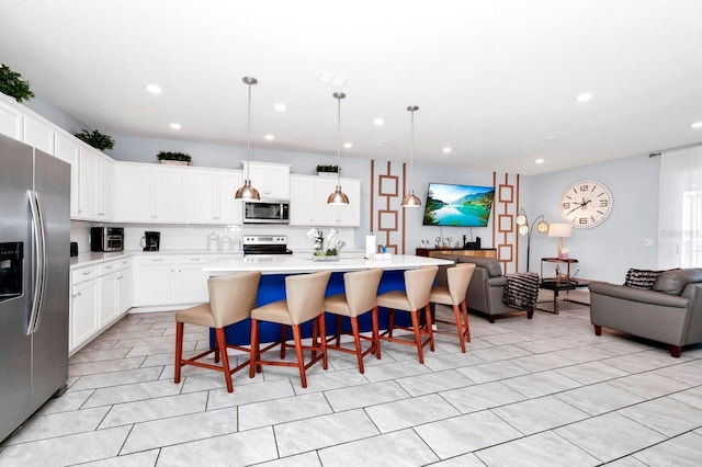 kitchen with pendant lighting, a kitchen breakfast bar, stainless steel appliances, and an island with sink