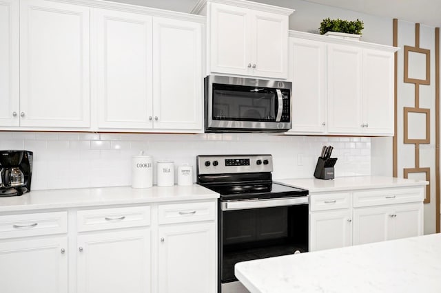 kitchen with white cabinetry, appliances with stainless steel finishes, light stone counters, and tasteful backsplash