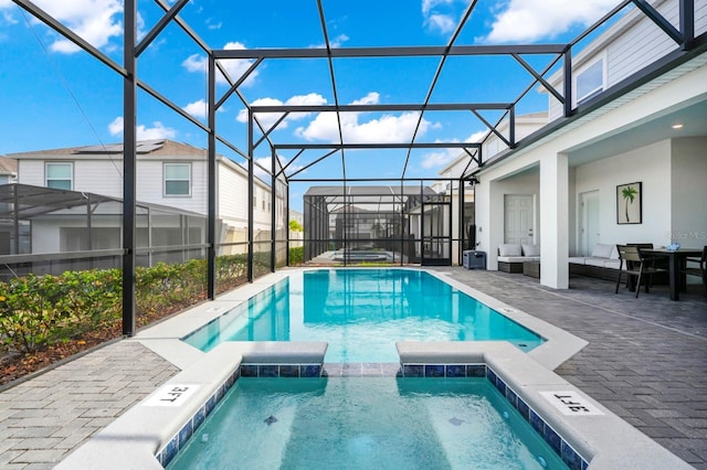 view of pool with a lanai, a patio area, outdoor lounge area, and an in ground hot tub