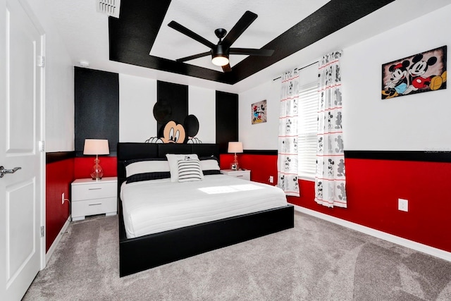 carpeted bedroom featuring a tray ceiling and ceiling fan