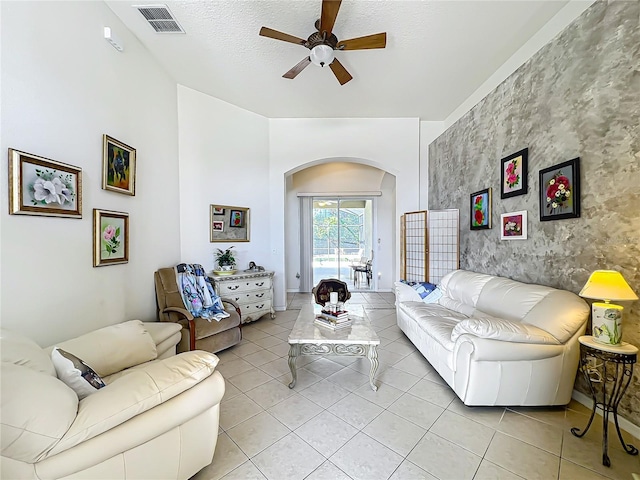 living room featuring ceiling fan, a textured ceiling, and light tile patterned floors