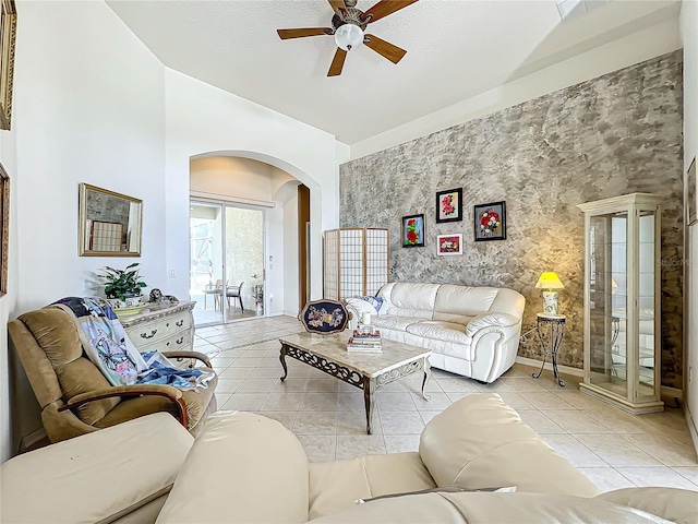 tiled living room featuring ceiling fan and a high ceiling