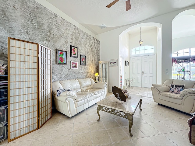 tiled living room with ceiling fan and a towering ceiling