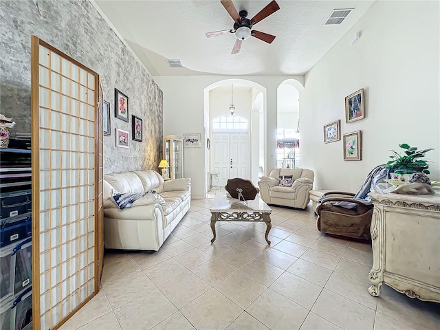 living room featuring ceiling fan, light tile patterned floors, and a textured ceiling