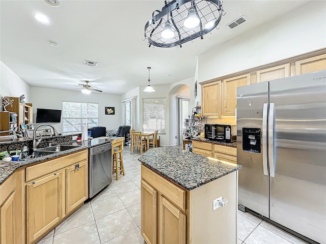 kitchen with decorative light fixtures, dark stone counters, sink, and stainless steel appliances