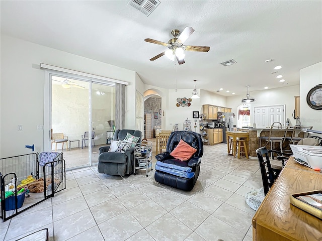 tiled living room with ceiling fan and a textured ceiling