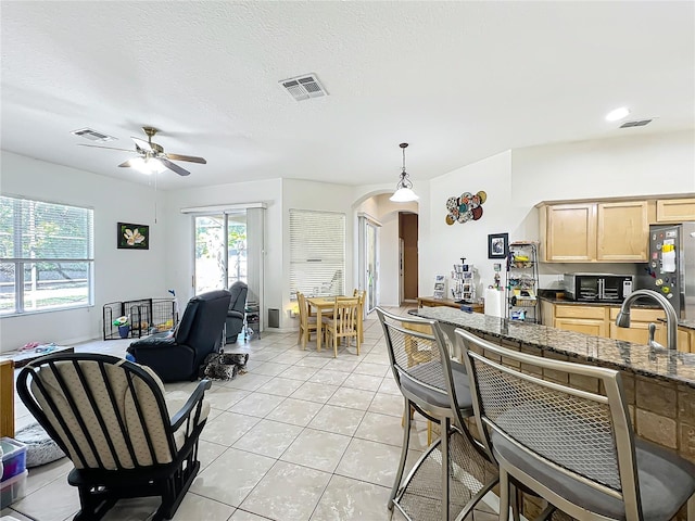 interior space with pendant lighting, a textured ceiling, light brown cabinetry, sink, and light tile patterned floors