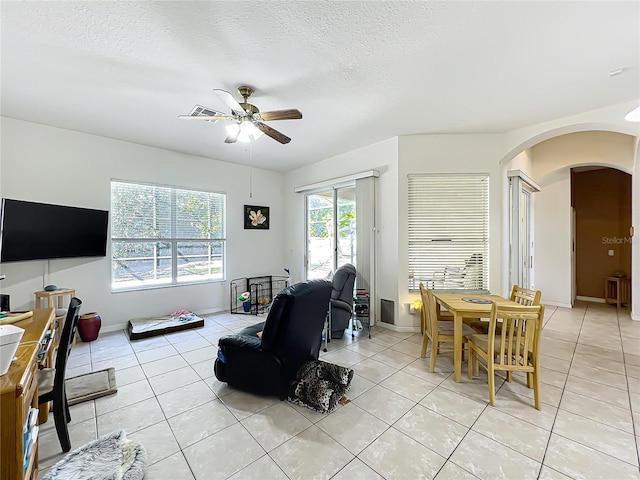 living room with ceiling fan, a textured ceiling, and light tile patterned floors