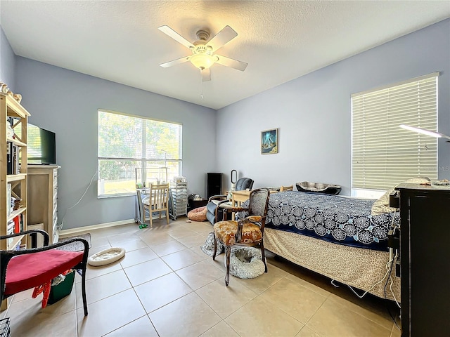 tiled bedroom with ceiling fan and a textured ceiling