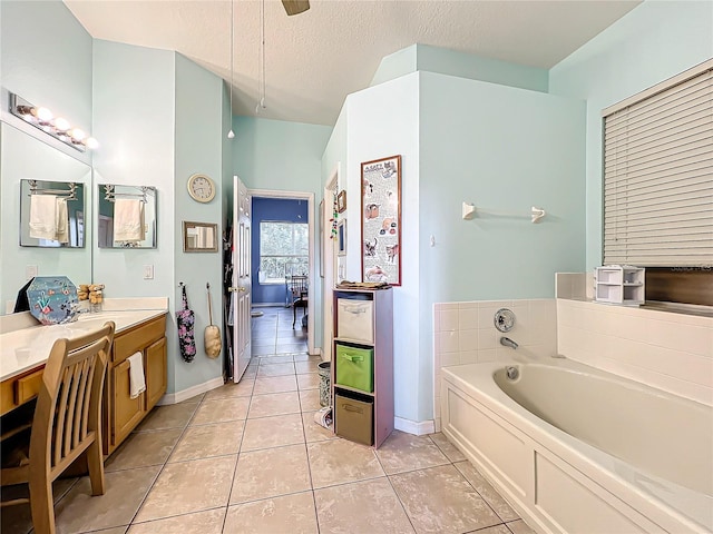 bathroom with a bathtub, vanity, tile patterned flooring, and a textured ceiling