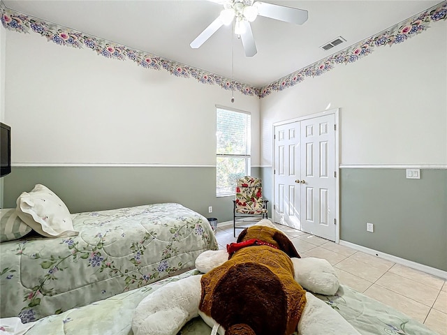 tiled bedroom with ceiling fan and a closet